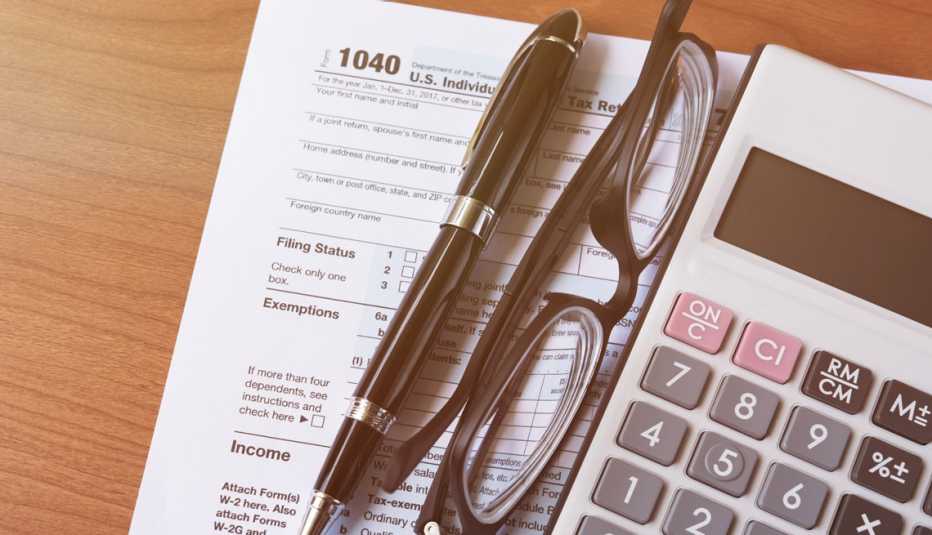 Formulario 1040 del IRS enseguida de una calculadora, unas gafas y un lapicero