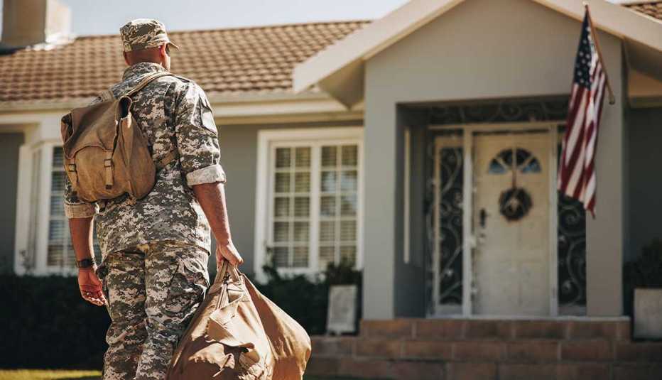 Soldado del ejército frente a una casa con la bandera de Estados Unidos