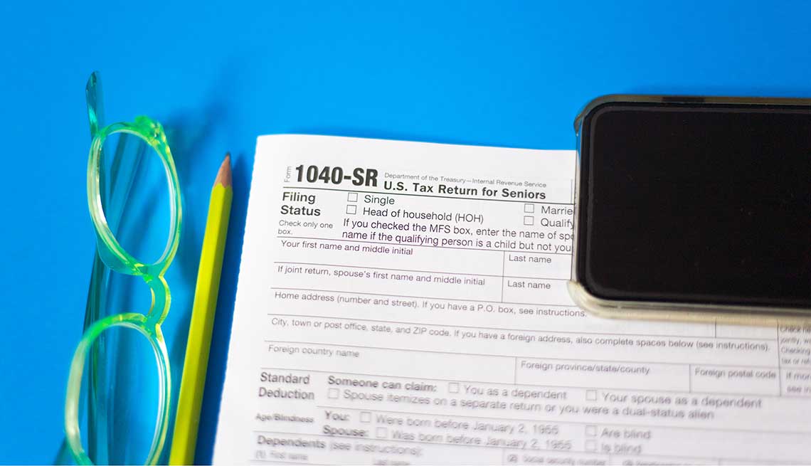 Formulario 1040-SR del IRS al lado de un lápiz y unas gafas