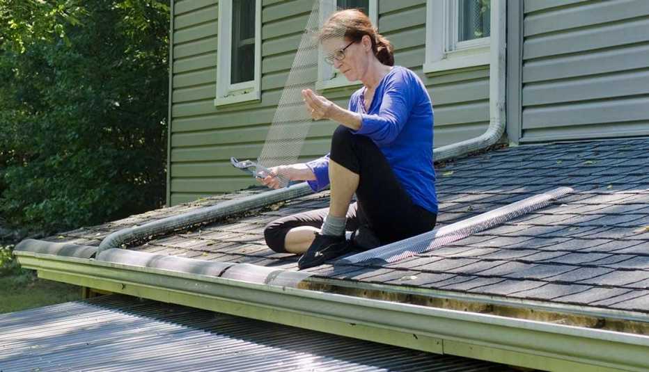 Mujer protegiendo los canales del desagüe del techo de su casa