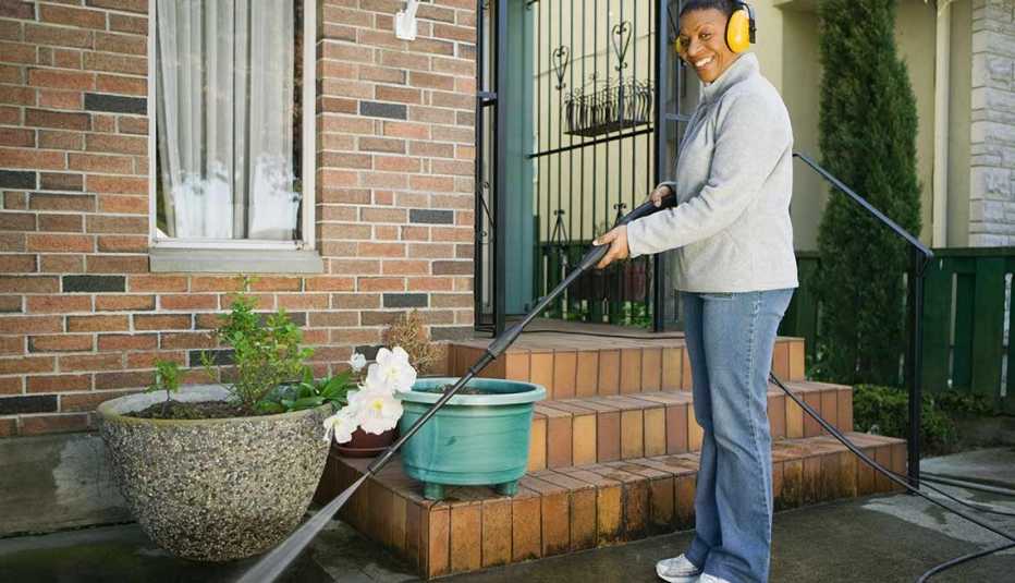 Mujer lavando el patio de su casa