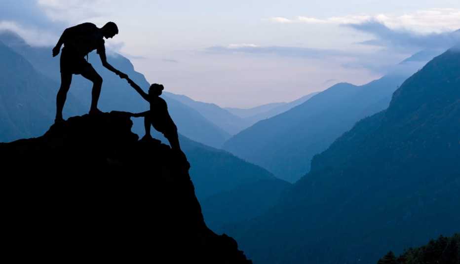 Hombre dándole la mano a una mujer que llega a la cima de una montaña - Becas universitarias inusuales