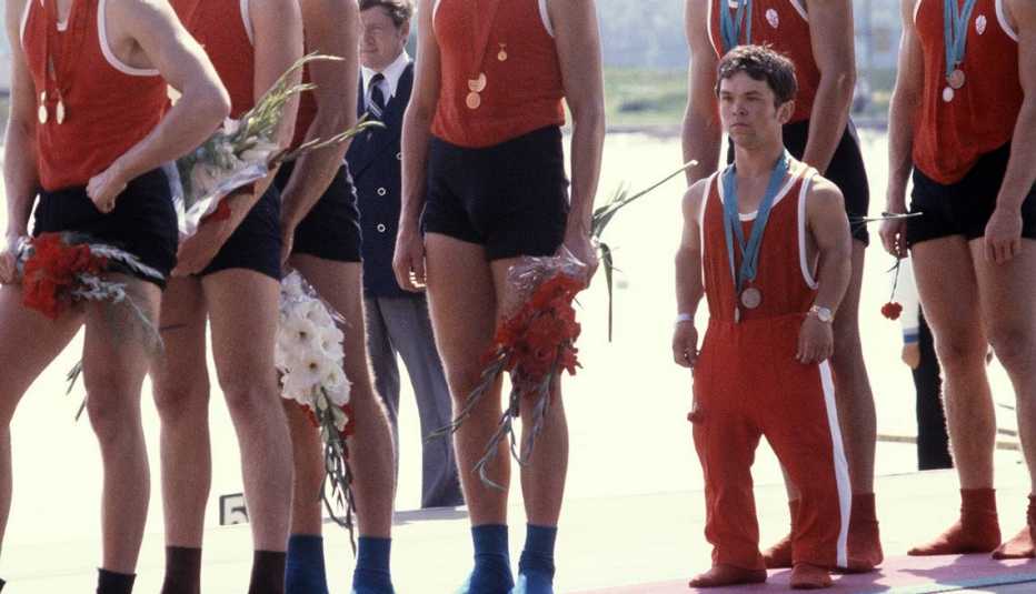 Hombre pequeño con traje de atletismo al lado de las piernas de hombres altos - Becas universitarias inusuales