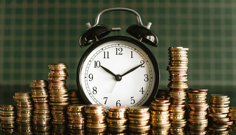 Reloj de mesa con campanas rodeado de monedas