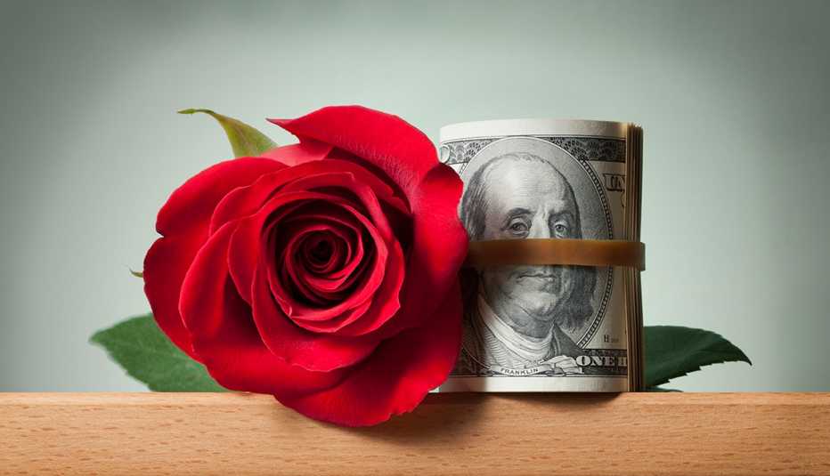 Una rosa al lado de un fajo de dólares envueltos