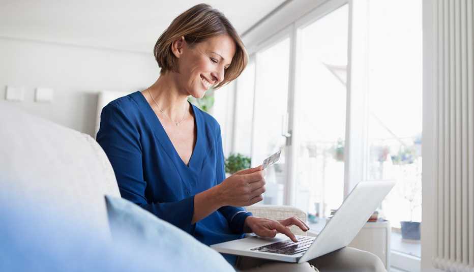 Mujer viendo facturas y con una computadora portátil sobre las piernas
