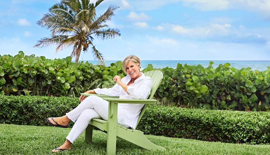 Suze Orman sentada en una silla con una playa al fondo