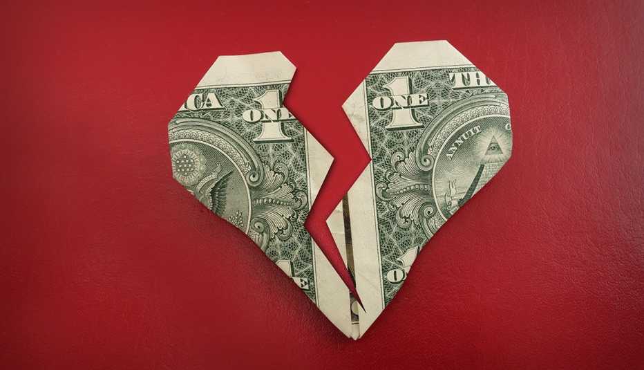 Billete de dólar doblado con estilo de origami en forma de un corazón roto. 