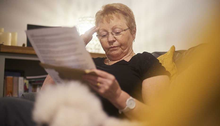 Mujer leyendo un documento que sostiene con una mano