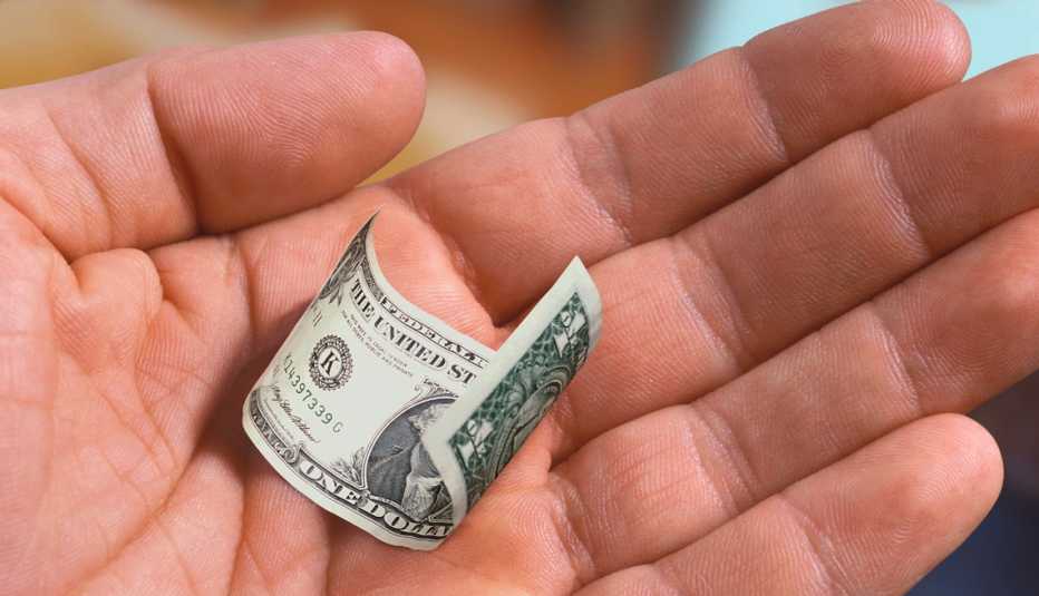 Una mano que sostiene un pequeño billete de dólar