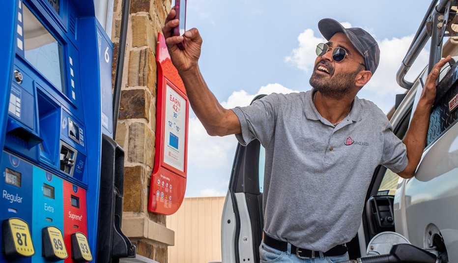 Hombre mirando el tablero de un distribuidor de gasolina mientras tanquea su camioneta