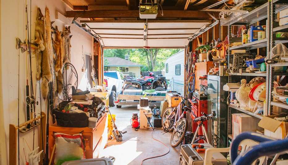 Garaje con estantes llenos con herramientas, elementos de aseo, decoraciones de temporada, juguetes, y equipos para deportes.