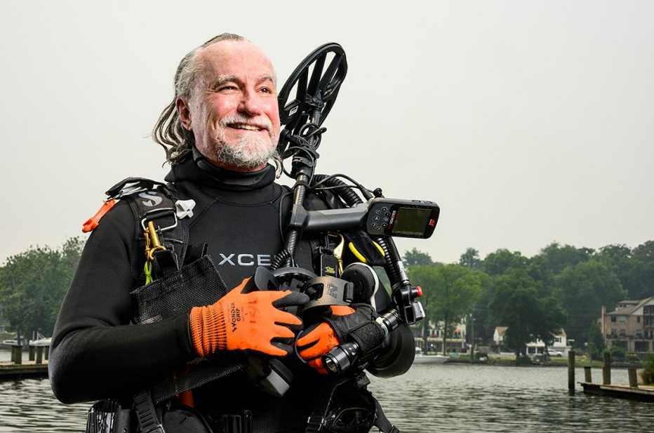 Rob Ellis con traje de buzo y un detector de metales submarino saliendo del rio Occoquan en Virginia