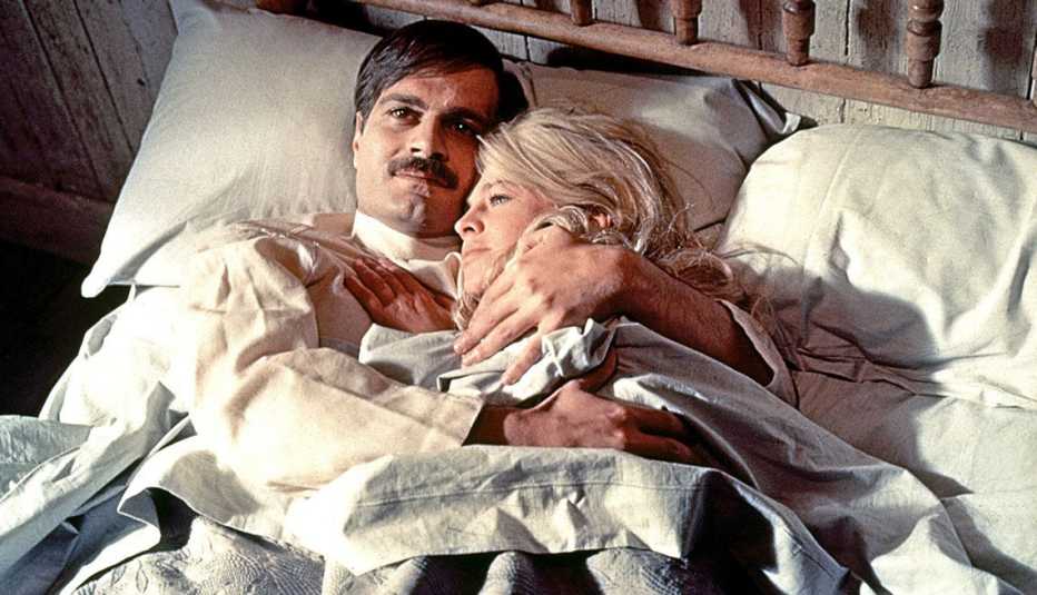 Una escena de Doctor Zhivago en la que aparece  Omar Sharif abrazando a una mujer mientras ambos están acostados en una cama.
