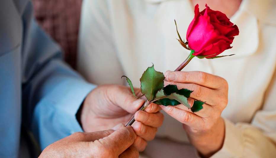 Hombre y mujer sostienen una rosa en sus manos.