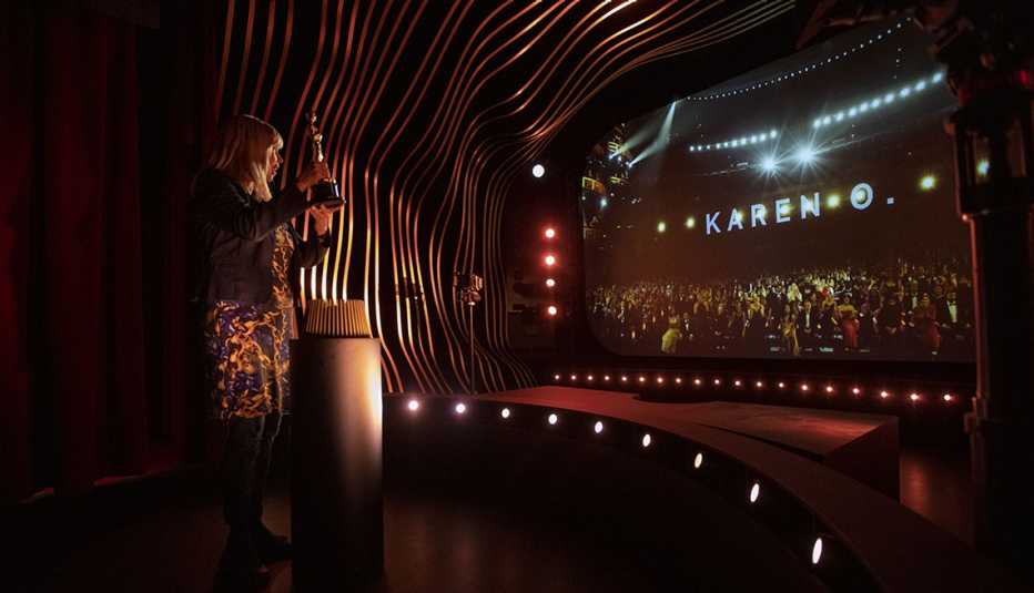 Una mujer sosteniendo un trofeo Oscar en la exposición Oscar Experience del Academy Museum of Motion Pictures.