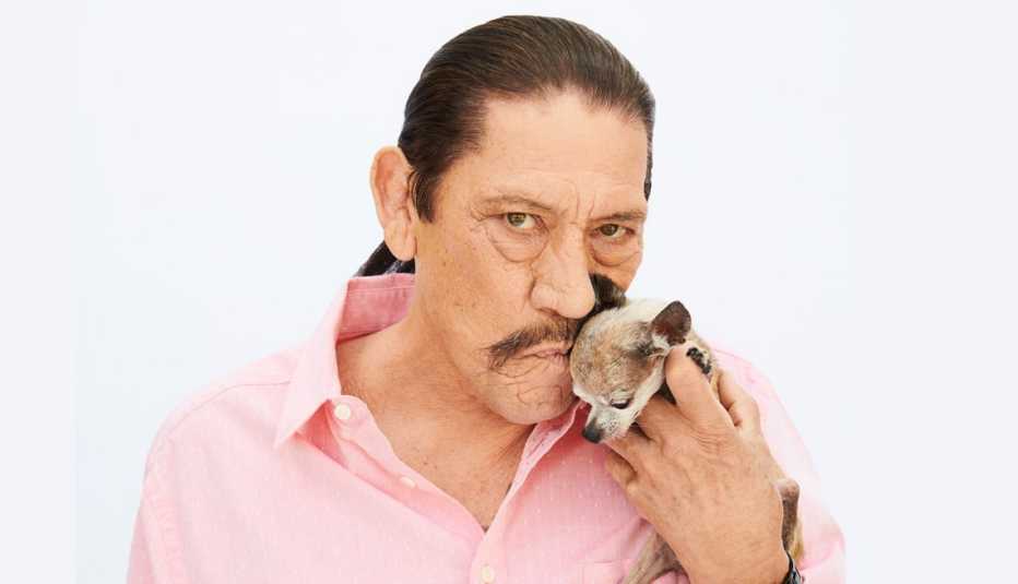 El actor Danny Trejo sosteniendo un chihuahua.