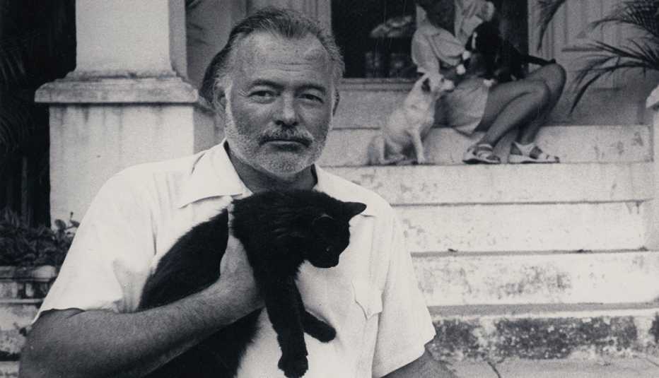 Ernest Hemingway sosteniendo un gato en su casa en Cuba.