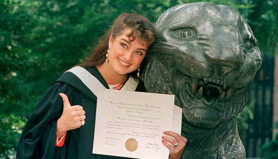 Brooke Shields muestra su diploma mientras posa junto a la mascota de la universidad el día de su graduación de Princeton