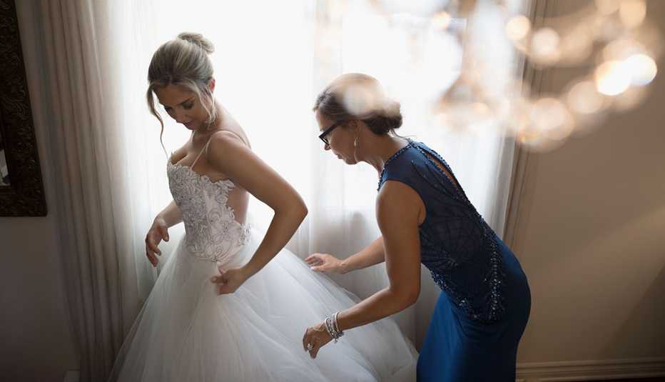 Mujer vestida de novia con su madre arreglando el vestido