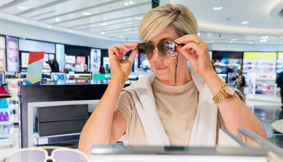 Mujer colocándose unos lentes de sol en una tienda de un aeropuerto.