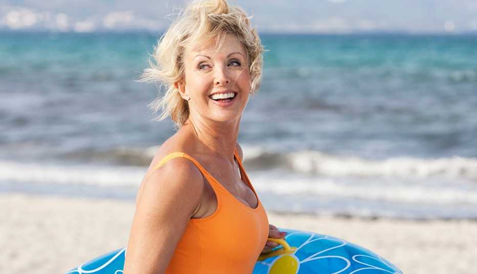 Mujer en una playa sosteniendo un flotador.