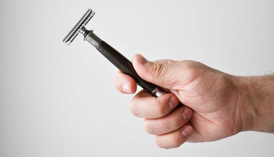 Un primer plano de la mano de un hombre sosteniendo una navaja de afeitar.