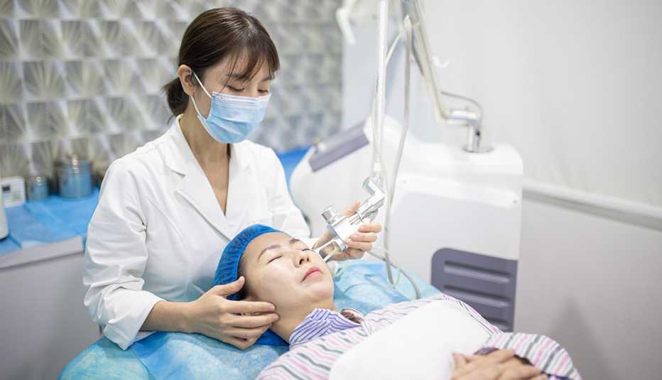 Mujer recibiendo tratamiento facial con láser.