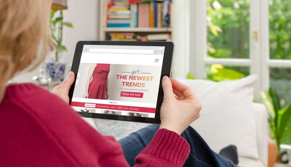 Mujer sentada en casa mirando una tableta digital y está navegando en internet y comprando.