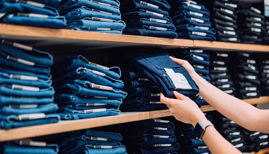 Una mujer sosteniendo un par de jeans en una tienda de ropa.
