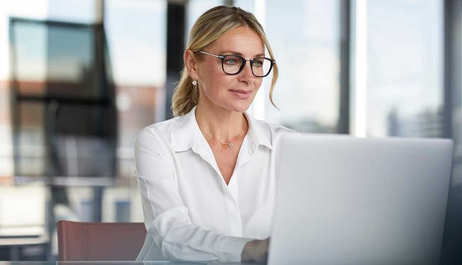 Una mujer trabajando en la oficina, usando la computadora portátil.
