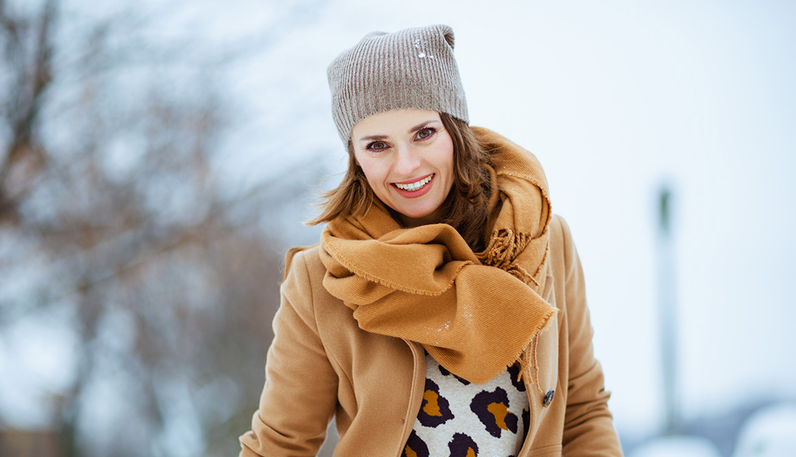 Una mujer con sombrero marrón, bufanda y abrigo al aire libre durante el invierno.