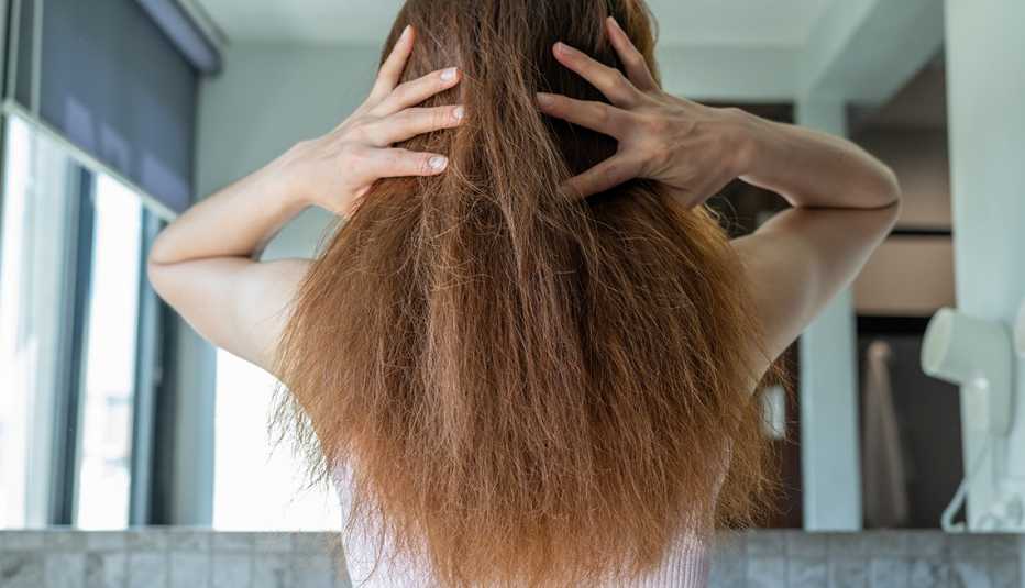 Una mujer sosteniendo el cabello dañado por el alto calor de los secadores de pelo.