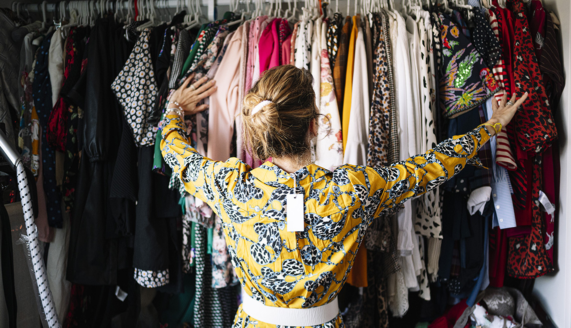 Una mujer de espalda mira su armario lleno de ropa.
