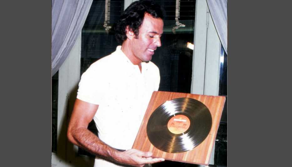 Julio Iglesias de vacaciones en Marbella, España sosteniendo un disco enmarcado en el 1975.