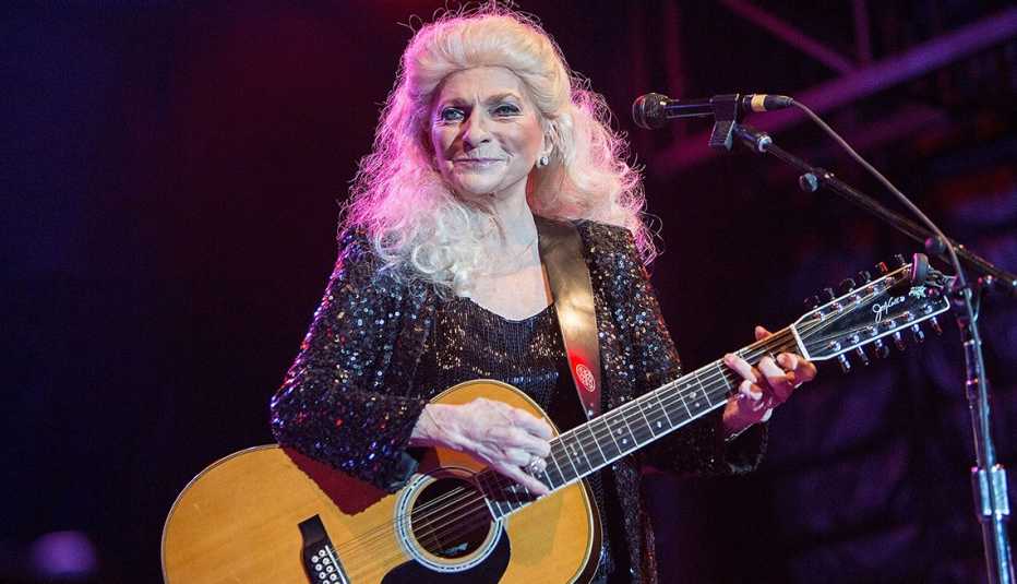 Judy Collins sosteniendo su guitarra durante una actuación en el escenario.