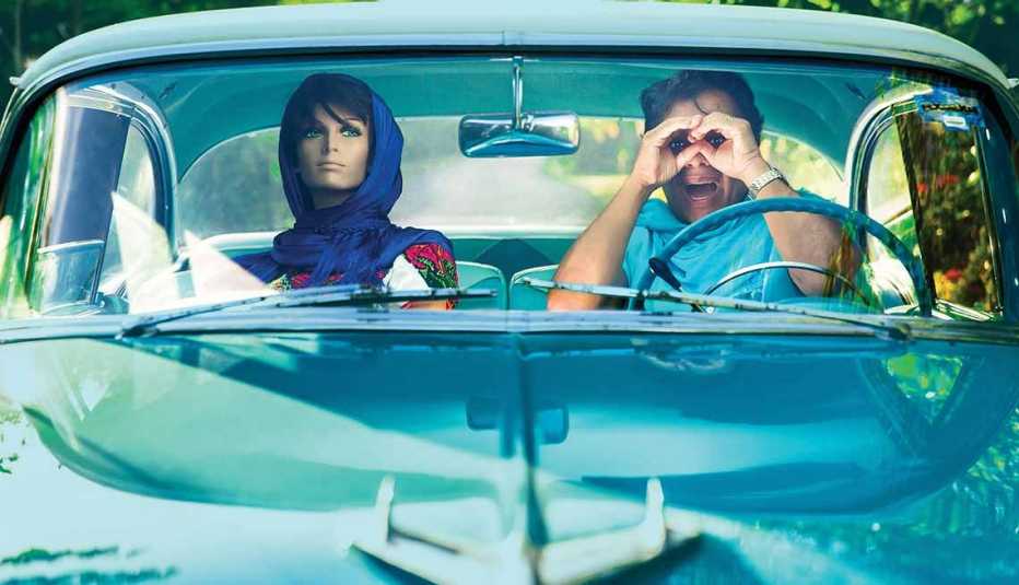 Juan Gabriel en un auto azul y un maniquí de copiloto
