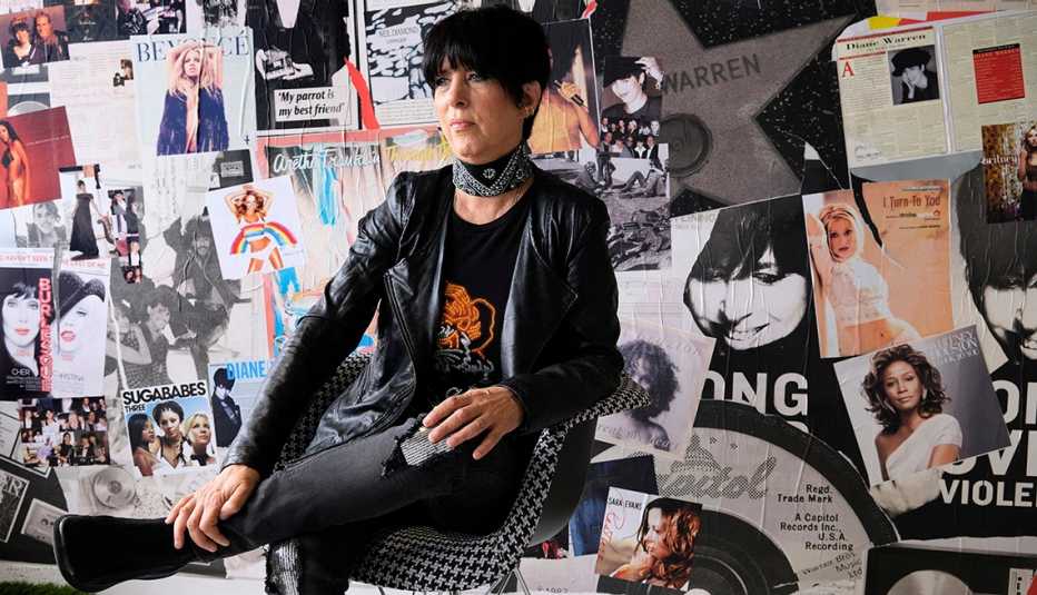 La compositora Diane Warren se sienta en una silla en su oficina y posa para un retrato frente a una pared llena de portadas de revistas y álbumes.