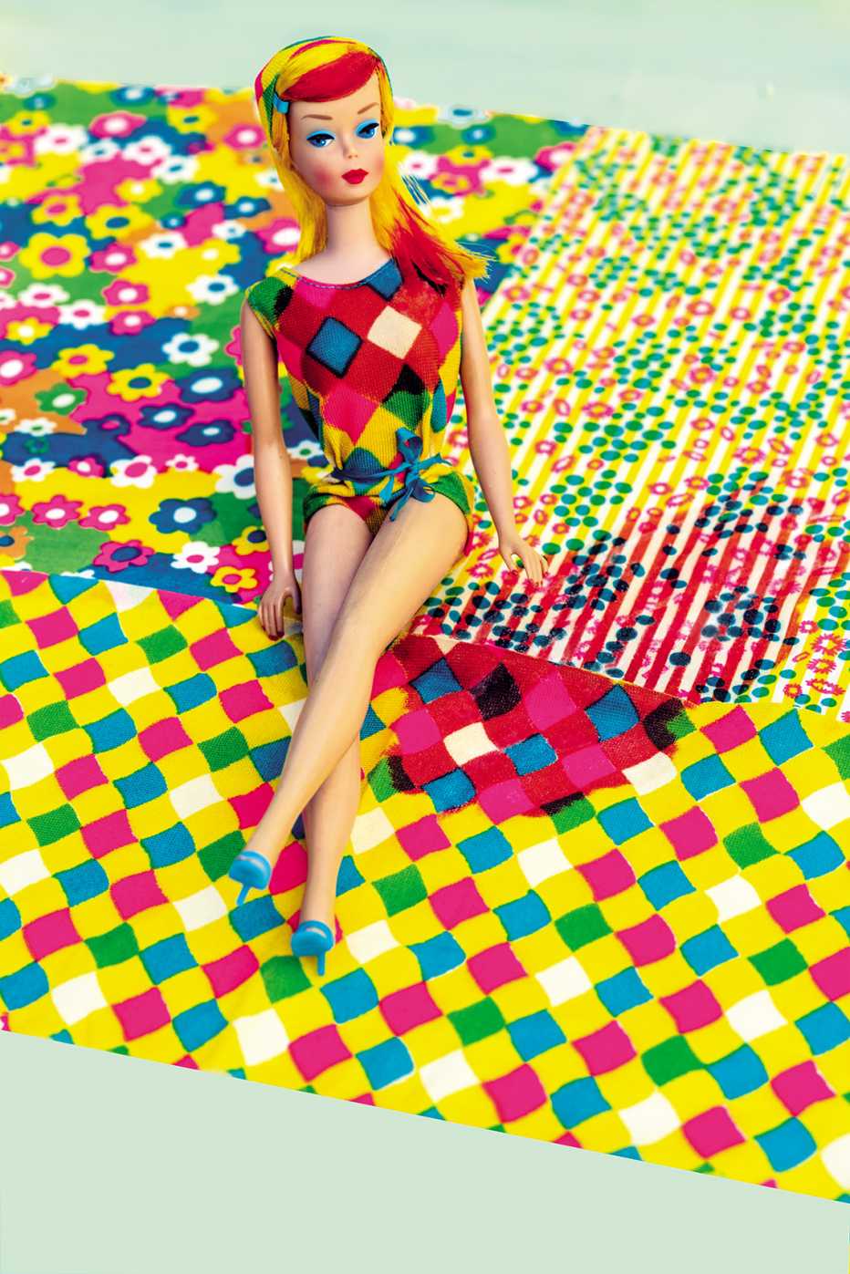 Muñeca Barbie sentada en unas mantas de colores que cambian. 