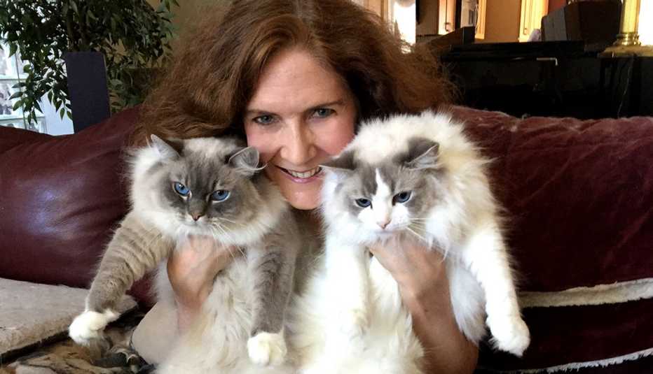 Mujer sostiene dos gatos junto a su cara