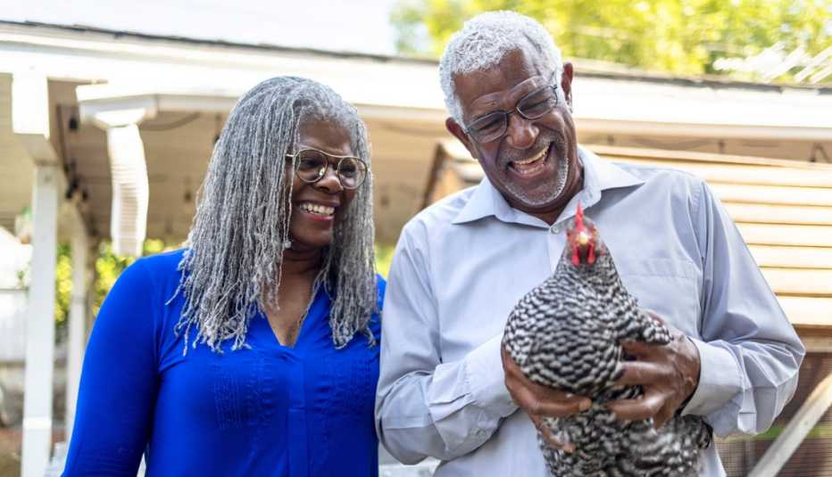 Un hombre mayor sostiene un pollo en sus manos