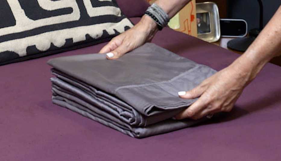 Coloca las fundas de almohada y la sábana superior sobre la sábana ajustable doblada