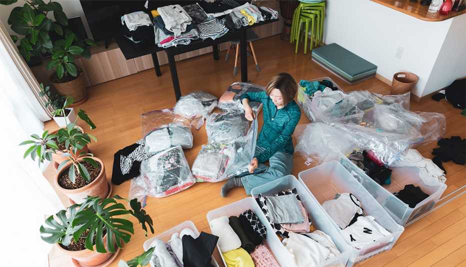 Una mujer organiza ropa en la sala de su casa