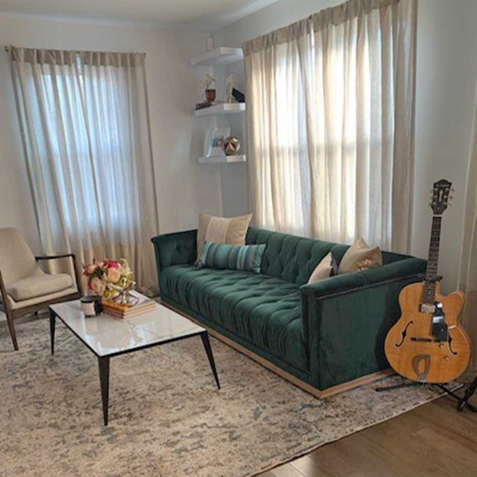 Una sala de estar con cortinas más claras, techos altos y muebles con patas de madera