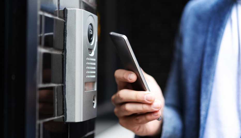 Una persona sostiene su teléfono frente a una cerradura inteligente