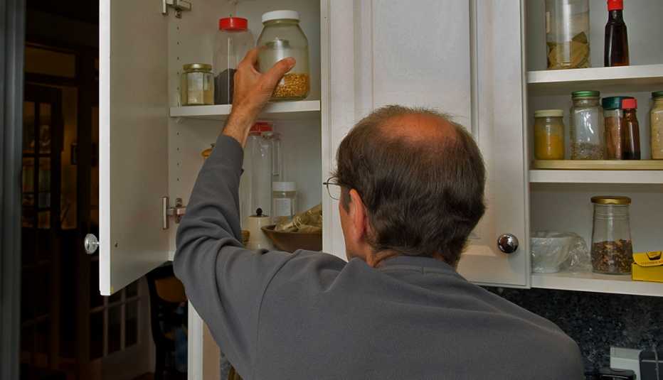 Hombre alcanza un frasco del gabinete en la cocina