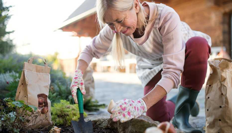 Mujer cava en su jardín para plantar bulbos