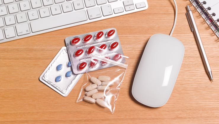 Medicamentos junto a un teclado y ratón de computador - Cómo usar las farmacias en internet