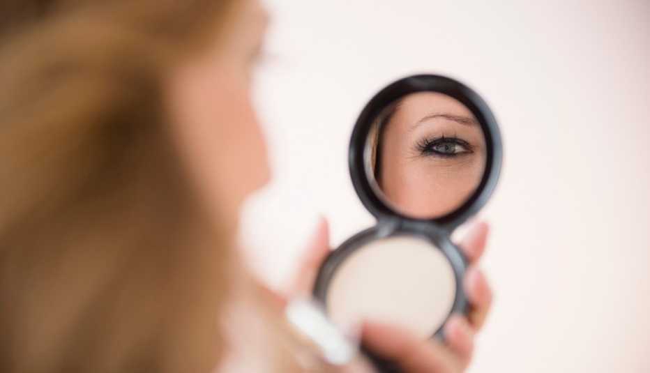 Una mujer mira en su espejo compacto para comprobar su maquillaje