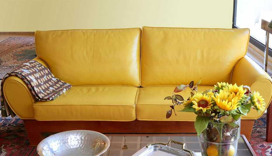 Mueble color mostaza detrás de una mesa con un florero lleno de girasoles